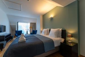 a bedroom with a large bed with two blue chairs at Hof van Slenaken - Hotel & Apartments in Slenaken