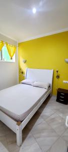a white bed in a room with a yellow wall at LA MENOR in Ribeira Grande
