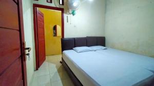 a small bedroom with a bed and a red door at Aqsa Guest House Banjarsari in Banjarsari
