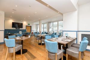 a restaurant with wooden tables and blue chairs at Portbyhan Hotel in Looe