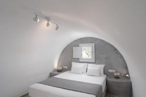 una camera con un letto bianco e una parete bianca di White Lily Santorini - Adults Only 16 Plus a Perivolos