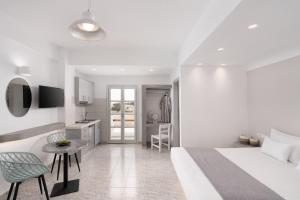 een witte slaapkamer met een bed en een tafel en stoelen bij White Lily Santorini - Adults Only 16 Plus in Perivolos