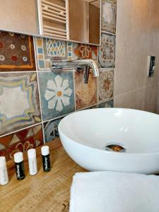a bathroom with a white sink and some tiles at Canal Vena Suite House by ApartSuite in Chioggia +12 photos