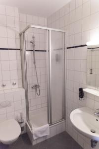 a bathroom with a shower and a toilet and a sink at Hotel Cosima in Vaterstetten
