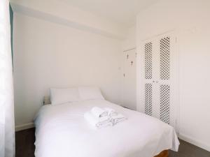 - une chambre avec un lit blanc et des serviettes dans l'établissement Pass the Keys - Comfy Flat in the hart of Central London, à Londres