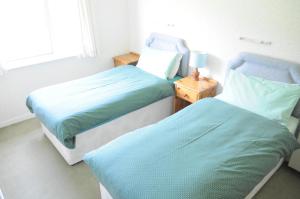 two beds in a room with blue sheets at Lamont Chalets in Glenelg