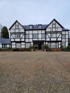 une grande maison noire et blanche avec une allée en gravier dans l'établissement Purdis Farm - Flat 4, à Bucklesham