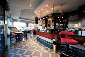 um restaurante com um bar com bancos vermelhos em Hotel Michelangelo em Biella