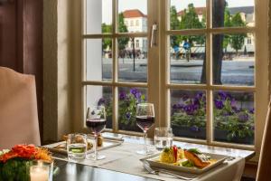 a table with a glass of wine and a plate of food at NH Brugge in Bruges
