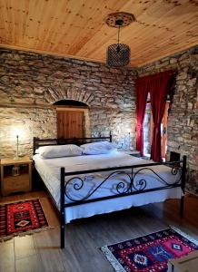 1 dormitorio con 1 cama grande en una pared de piedra en Stone rooms 1850, en Gjirokastra