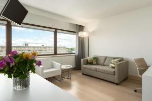 a living room with a couch and a table with flowers at NH Amsterdam Zuid in Amsterdam