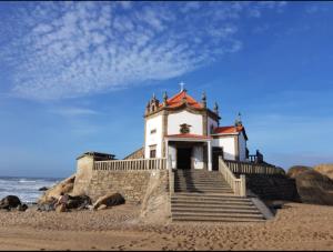 un edificio su una spiaggia con scale e l'oceano di Apartamento Francelos Condominio a Vila Nova de Gaia