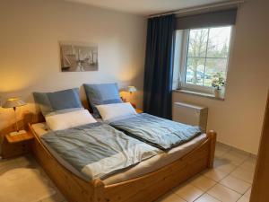 Schlafzimmer mit einem Bett mit blauer Bettwäsche und einem Fenster in der Unterkunft Buxbuddies Captains Inn in Fehmarn
