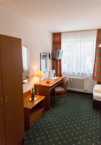 a hotel room with a desk and a bed at Hotel Cosima in Vaterstetten
