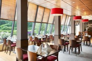 a dining room with tables and chairs and windows at NH Capelle Rotterdam in Capelle aan den IJssel