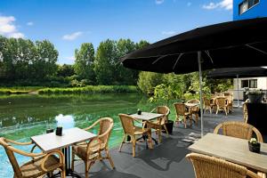 a patio with tables and chairs next to a river at NH Capelle Rotterdam in Capelle aan den IJssel