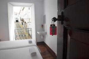 1 dormitorio con cama, lavabo y ventana en Pensión Santa Cristina, en Santiago de Compostela