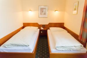 two beds in a hospital room with lights on at Hotel Cosima in Vaterstetten