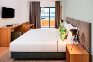 a bedroom with a large white bed and a television at NH Marina Portimao Resort in Portimão