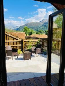 a view of a patio with chairs and a fence at The Fox's Den, Luxury Cosy Mini Lodge, Highlands in North Ballachulish
