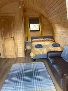 The Fox's Den, Luxury Cosy Mini Lodge, Highlands في North Ballachulish: غرفة صغيرة بها سريرين وأريكة