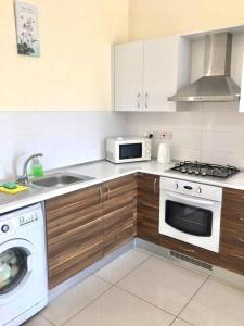 eine Küche mit Herd, Spüle und Mikrowelle in der Unterkunft Luxury Two-Bedroom Apartment in amazing place Lukomorye C4 in Alsancak