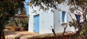 a white house with blue doors and trees at Simos suites in Elafonisos