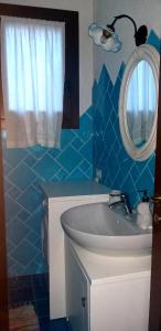 Baño de azulejos azules con lavabo y espejo en Casetta Francy, en San Teodoro