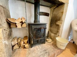 a wood stove in a room with a pile of wood at Normanby Cottage Runswick Bay in Runswick