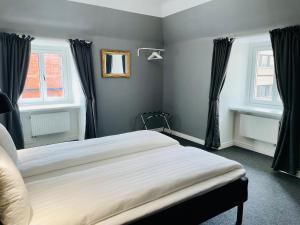 a bedroom with a bed and two windows at Birka Hotel in Stockholm