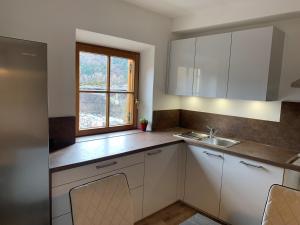 a kitchen with white cabinets and a sink and a window at Appartment Valentin in Chiusa