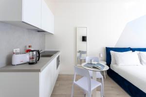 a bedroom with a bed and a table and a kitchen at Italianway - The B Village Business in Milan