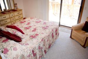 a bedroom with a bed with a floral bedspread and a dresser at 10328 - 28 Opalo Place in Hot Springs Village