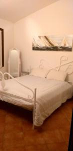 a white bed in a white bedroom with a picture on the wall at Casetta Francy in San Teodoro