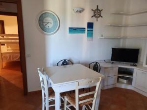 a dining room with a table and a tv and a clock at Casetta Francy in San Teodoro