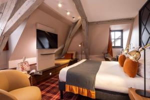a hotel room with a bed and a flat screen tv at Hotel Le Colombier in Colmar