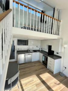 a large kitchen with a table and a staircase at Whispering Waves in Porthtowan @ Cornwall Coastal Holidays in Porthtowan