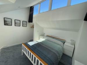 a bedroom with a bed in a room with windows at Whispering Waves in Porthtowan @ Cornwall Coastal Holidays in Porthtowan