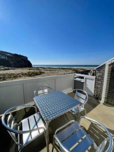 d'une table et de chaises sur un balcon donnant sur l'océan. dans l'établissement Whispering Waves in Porthtowan @ Cornwall Coastal Holidays, à Porthtowan