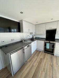 a kitchen with white cabinets and a wooden floor at Whispering Waves in Porthtowan @ Cornwall Coastal Holidays in Porthtowan