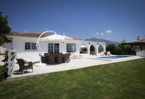 a patio with chairs and an umbrella in front of a house at Fantastic renovated villa annex in Mijas Costa