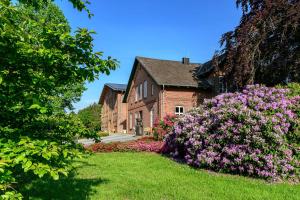 a brick house with pink flowers in front of it at Nutzwedel Resort Farmers Lodge in Horst in Holstein