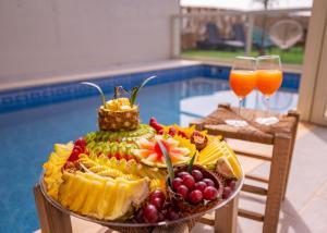 a plate of fruit on a table with two glasses of juice at Blue lake luxury villa for families in ‘Ein el Asad