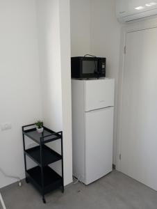 einen weißen Kühlschrank mit einer Mikrowelle darüber in der Unterkunft נוף לחרמון in Kibbuz Dafna