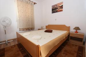 a bedroom with a bed and a fan and a window at Apartments Ana - Kustići in Novalja