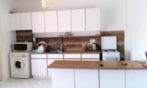 eine Küche mit weißen Schränken, einer Waschmaschine und einem Trockner in der Unterkunft 1 bedroom apartment with a magnificent sea view in Limassol