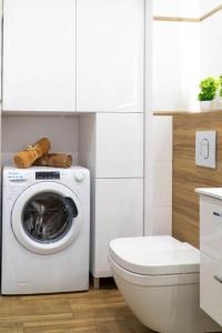 uma casa de banho branca com uma máquina de lavar roupa e um WC em Apartament przy Czarnej em Bialystok