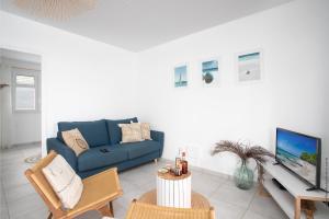 uma sala de estar com um sofá azul e uma televisão em Villa Kaliemma em Le Marin