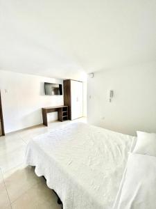 1 dormitorio blanco con 1 cama grande y TV en HERSUA HOTEL BOUTIQUE, en Duitama