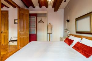 1 dormitorio con 1 cama blanca grande con almohadas rojas en Alameda Suites Apartments, en Sevilla